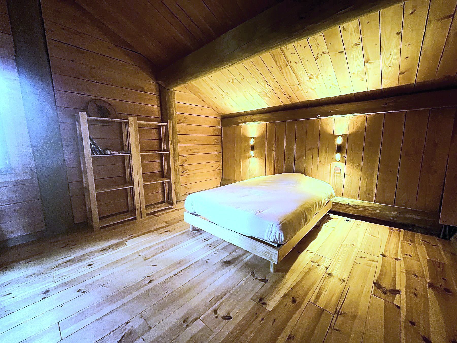 Chambre double en bois, lumière chaude, lit et étagères