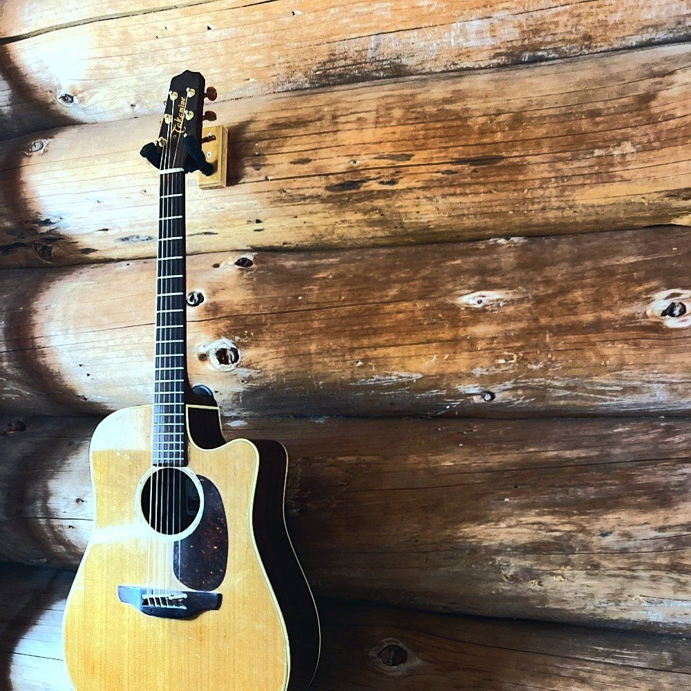 Guitare acoustique accrochée au mur en rondins