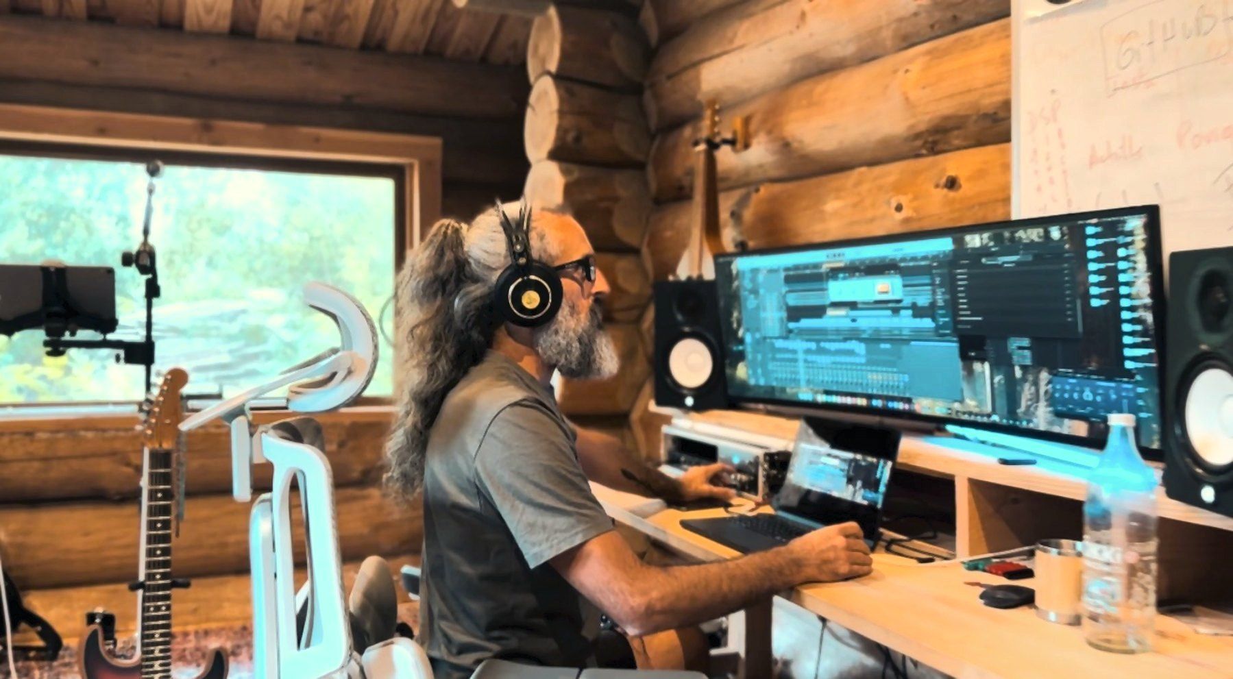 Simon au mixage dans La Petite Rebelle : écran Logic Pro, enceintes de proximité, murs en rondins
